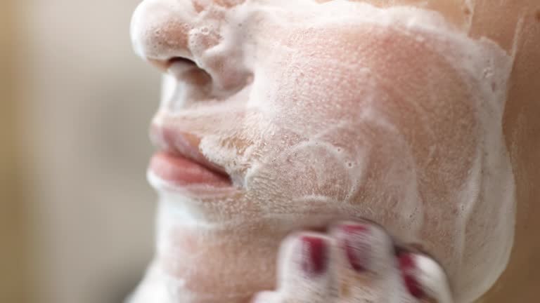 Facial Cleanser - istockphoto, Young woman is washing applying foam cleanser on face. Daily facial skincare procedure. Beauty treatment at home. She is rubbing and massaging her face.